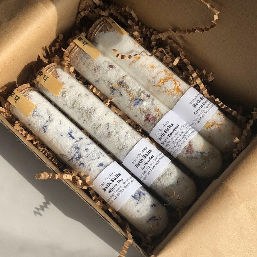 The Explorer Set with 4 mini bath salt soaks in glass tubes with cork lids, featuring floral-infused Epsom salt blends and organic ingredients.