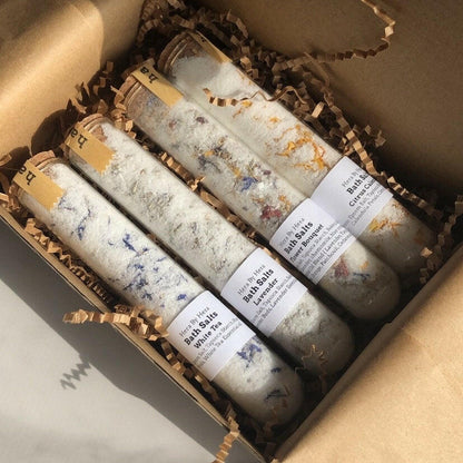The Explorer Set with 4 mini bath salt soaks in glass tubes with cork lids, featuring floral-infused Epsom salt blends and organic ingredients.
